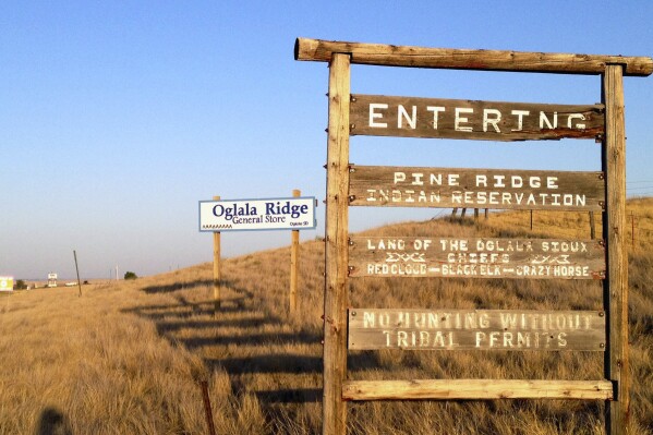 FILE - A sign hands outside the entrance to the Pine Ridge Indian Reservation in South Dakota, home to the Oglala Sioux tribe, Sept. 9, 2012. A tribe has banned Republican Gov. Kristi Noem from the Pine Ridge Reservation after she spoke this week about wanting to send razor wire and security personnel to Texas to help deter immigration at the U.S.-Mexico border and also said cartels are infiltrating the state's reservations. (AP Photo/Kristi Eaton, File)