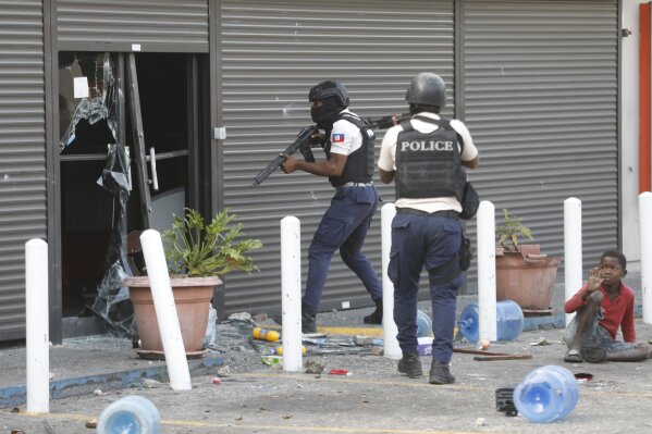 Police prepare to enter a vandalized grocery store, during a protest to demand the resignation of Prime Minister Ariel Henry in the Petion-Ville neighborhood of Port-au-Prince, Haiti, Tuesday, Feb. 6, 2024. (AP Photo/Odelyn Joseph)