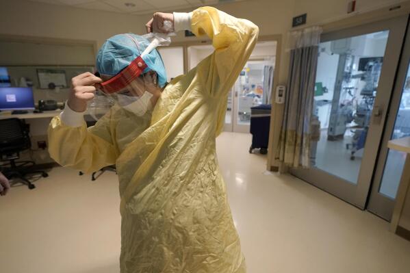 FILE - Registered nurse Sara Nystrom, of Townshend, Vt., prepares to enter a patient's room in the COVID-19 Intensive Care Unit at Dartmouth-Hitchcock Medical Center, in Lebanon, N.H., Jan. 3, 2022. The omicron variant has caused a surge of new cases of COVID-19 in the U.S. and many hospitals are not only swamped with cases but severely shorthanded because of so many employees out with COVID-19. (AP Photo/Steven Senne, File)