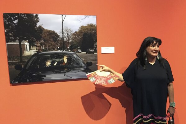 FILE - In this July 27, 2016 file photo, acclaimed Mexican American author Sandra Cisneros points to a photograph by Cecil McDonald, Jr., at the National Hispanic Cultural Center in Albuquerque, N.M. at an exhibit based by her 1984 novel "The House On Mango Street." Cisneros told the radio show Latino USA radio host Maria Hinojosa on Wednesday, Jan. 29, 2020, that she appreciated the work by Jeanine Cummins and didn't understand the criticism her novel, "American Dirt" is facing about Mexican stereotypes. (AP Photo/Russell Contreras, File)
