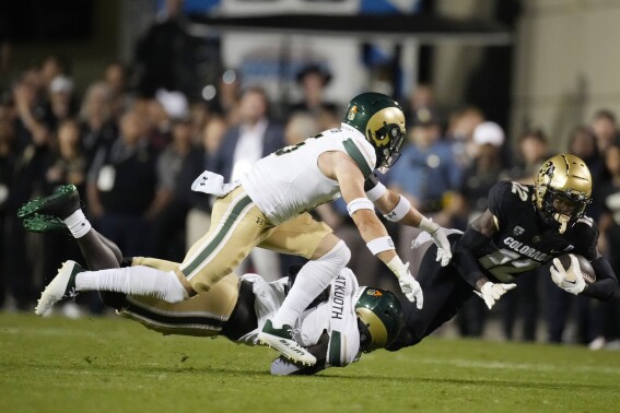 Colorado cornerback Travis Hunter (12) is dragged down after a short gain by Colorado State defensive back Henry Blackburn, back left, and defensive back Ayden Hector during the first half of an NCAA college football game Saturday, Sept. 16, 2023, in Boulder, Colo. (AP Photo/David Zalubowski)