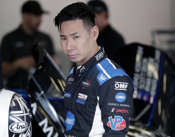 FILE - Kamui Kobayashi, of Japan, walks by his car in his garage before a practice session during testing for the upcoming Rolex 24 hour auto race at Daytona International Speedway, Jan. 3, 2020, in Daytona Beach, Fla. The NASCAR Cup Series race at Circuit of the Americas, Sunday, March 24, 2024, will be first of five on road or street courses this season and Kobayashi will be competing for 23XI Racing. (AP Photo/John Raoux, File)