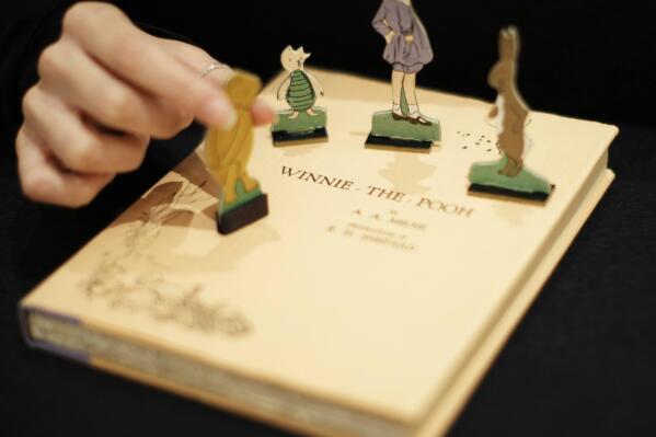 FILE - A first U.S. edition of Winnie the Pooh signed by the author A.A. Milne and illustrator E.H. Shepard is displayed with cut-outs representing characters from the book at offices of the Sotheby's auction house in London, Monday, Dec. 15, 2008.   “Winnie the Pooh” and “The Sun Also Rises” are going public. A.A. Milne’s children’s book and Ernest Hemingway’s novel are among the works from 1926 whose copyrights will expire Saturday, Jan. 1, 2022, putting them in the public domain in 2022.  (AP Photo/Matt Dunham, File)