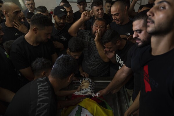 Mourners chant anti Israel slogans while they take the last look at the body of Fares Abu Samra, 14, during his funeral in the West Bank city of Qalqilya, Thursday, July 27, 2023. The Palestinian Health Ministry said Thursday that Abu Samra was killed by Israeli fire in Qalqilya. The Israeli military said Palestinians threw rocks and firebombs at troops, who responded by firing into the air. It said the incident was being reviewed. (AP Photo/Nasser Nasser)