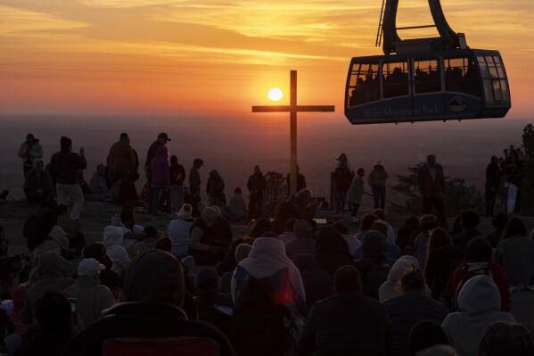 The sun rises behind a cross as hundreds attend the Easter sunrise service on top of Stone Mountain in Stone Mountain, Ga., on Sunday, March 31, 2024. (Ben Gray/Atlanta Journal-Constitution via AP)
