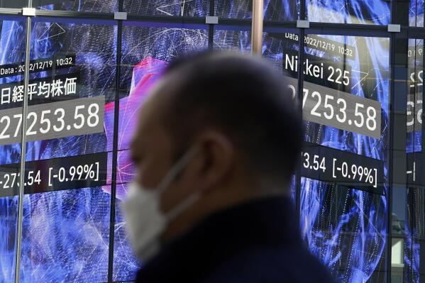 A person stands near an electronic stock board showing Japan's Nikkei 225 index at a securities firm Monday, Dec. 19, 2022, in Tokyo. Asian stock markets fell again Monday as investors wrestled with fears the Federal Reserve and European central banks might be willing to cause a recession to crush inflation. (AP Photo/Eugene Hoshiko)