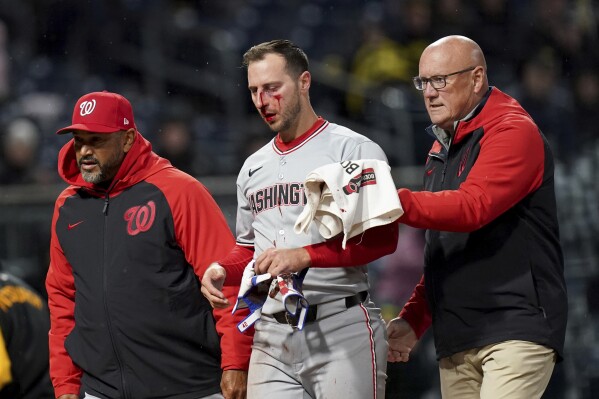 Washington Nationals' Paul DeJong, center, is helped off the field after getting hit by a pitch by Pittsburgh Pirates' Mitch Keller during the sixth inning of a baseball game Tuesday, April 15, 2025, in Pittsburgh. (AP Photo/Matt Freed)