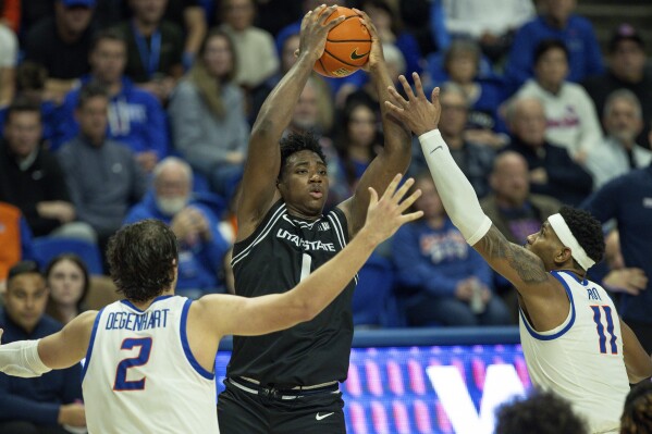 Utah State forward Great Osobor (1) tries to pass the ball against the defense of Boise State forward Tyson Degenhart (2) and guard Chibuzo Agbo (11) in the second half of an NCAA college basketball game, Saturday, Jan. 27, 2024, in Boise, Idaho. Utah State won 90-84. (AP Photo/Steve Conner)