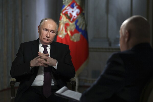 Russian President Vladimir Putin is interviewed by Rossiya Segodnya International Media Group Director General Dmitry Kiselev, back to a camera, in Moscow, Russia, Tuesday, March 12, 2024. (Gavriil Grigorov, Sputnik, Kremlin Pool Photo via AP)