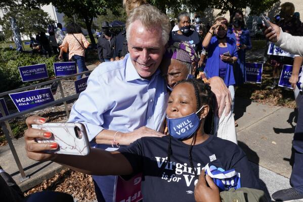 FILE - In this Oct. 17, 2021, file photo, Democratic gubernatorial candidate, former Virginia Gov. Terry McAuliffe, left, poses for a photo with supporters after a rally in Norfolk, Va. McAuliffe won Virginia's 2013 governor's race by embracing his own brand of personal politics that rely on decades-old friendships, back-slapping charisma and tell-it-like-it-is authenticity. (AP Photo/Steve Helber, File)