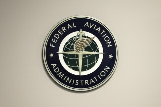 FILE - A Federal Aviation Administration sign hangs in the tower at John F. Kennedy International Airport in New York, March 16, 2017. Congressional negotiators have agreed on a $105 billion bill designed to improve the safety of air travel after a series of close calls between planes at the nation’s airports. (AP Photo/Seth Wenig, File)