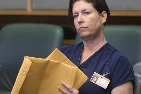 Defendant Sarah Boone holds envelopes during a pre-trial hearing in Orlando, Fla., Friday, June 7, 2024. Boone was arrested after detectives said her boyfriend died when he climbed into a suitcase as a joke and she zipped him inside. (Joe Burbank/Orlando Sentinel via AP)