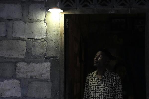 Bara Kilimandang looks up at a light bulb powered by solar energy at his house in Walatungga on Sumba Island, Indonesia, Tuesday, March 21, 2023. Around the world, hundreds of millions of people live in communities without regular access to power, and off-grid solar systems like these are bringing limited access to electricity to places like these years before power grids reach them. (AP Photo/Dita Alangkara)