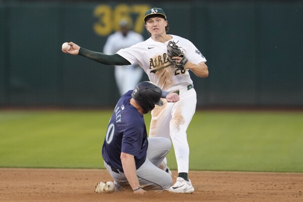 Oakland Athletics second baseman Zack Gelof, top, throws to first base after forcing Seattle Mariners' Luke Raley, bottom, out at second base on a double play hit into by Mitch Haniger during the fifth inning of a baseball game in Oakland, Calif., Tuesday, June 4, 2024. (AP Photo/Jeff Chiu)