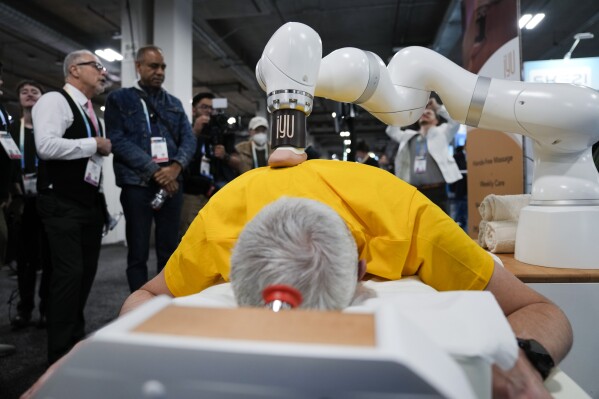 An attendee receives a massage from the iYU AI-assisted massage robot, by Capsix Robotics during the CES tech show Wednesday, Jan. 10, 2024, in Las Vegas. (AP Photo/Ryan Sun)