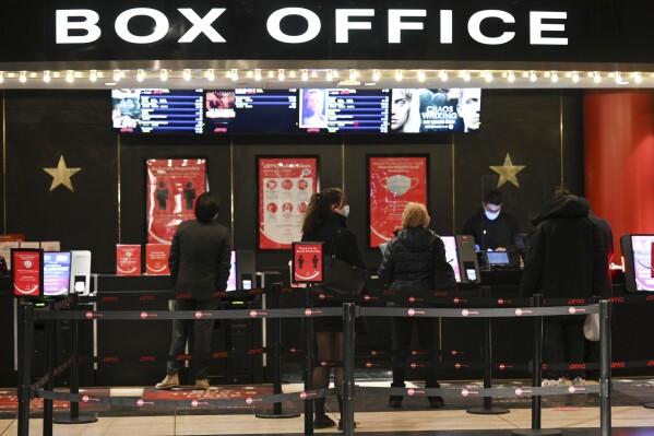 People purchase tickets at a movie theater in New York on March 5, 2021. (Photo by Evan Agostini/Invision/AP, File)