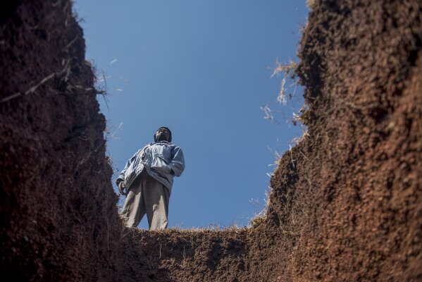 A worker stands next to a freshly-dug grave at the Honingnestkrans Cemetery, North of Pretoria, South Africa,  Thursday, July 9, 2020. The Africa Centers for Disease Control and Prevention says the coronavirus pandemic on the continent is reaching "full speed" after cases surpassed a half-million and a South African official said a single province is preparing 1.5 million grave. (AP Photo/Shiraaz Mohamed)