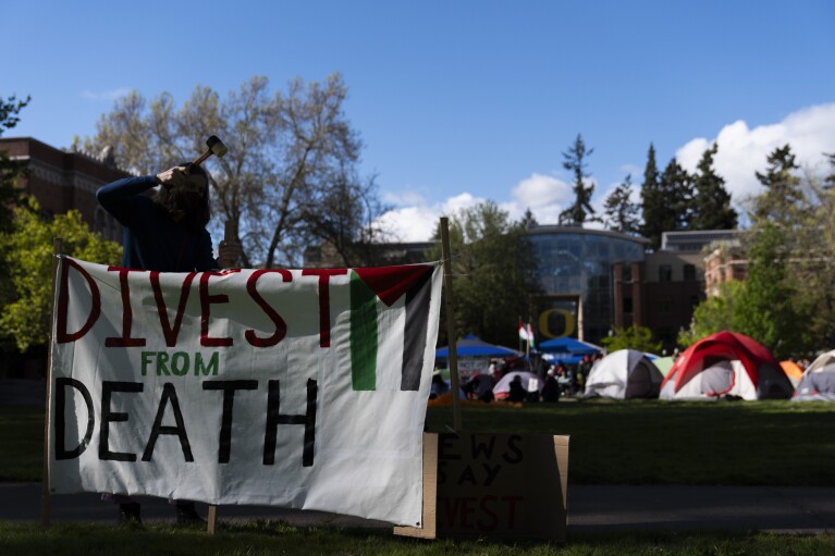Student Uniwersytetu w Oregonie zakłada tablicę do czytania "Odwróć się od śmierci" Studenci rozbili obóz namiotowy na uniwersytecie, aby zaprotestować przeciwko wojnie między Izraelem a Hamasem, poniedziałek, 29 kwietnia 2024 r., w Eugene w stanie Oregon.  (AP Photo/Jenny Kane)