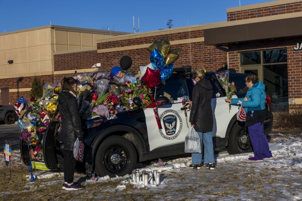 Three individuals holding flowers approach one of three memorials outside the Burnsville Police Department and City Hall building in Burnsville, Minn., on Tuesday, Feb. 20, 2024. Two police officers and a firefighter who responded to a domestic situation at a suburban Minneapolis home were killed early Sunday. (Kerem Yücel /Minnesota Public Radio via AP)