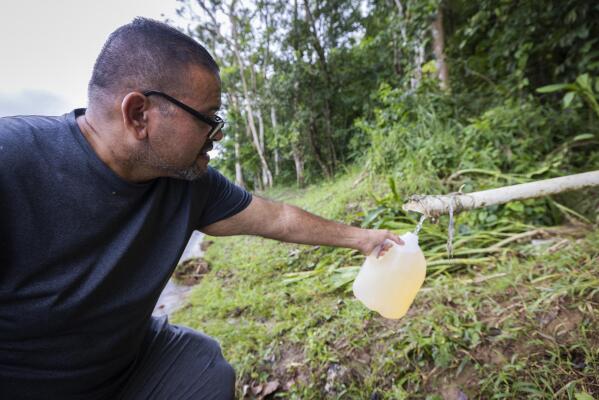 A man collects spring water from a mountain in Cayey, Puerto Rico, Tuesday, September 20, 2022. Locals have been forced to collect water from springs after Hurricane Fiona affected the water supply. (AP Photo/Alejandro Granadillo)