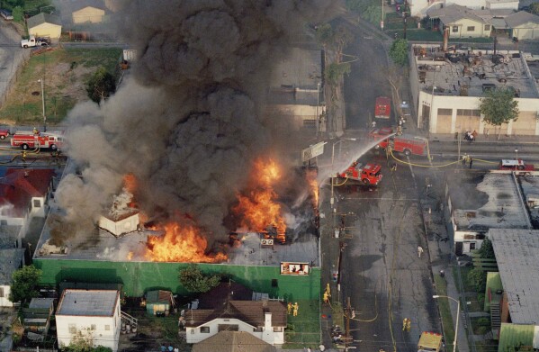 FILE - A fire burns out of control at the corner of 67th Street and West Boulevard in South Central Los Angeles, on April 30, 1992. On April 29, 1992, four white police officers were declared innocent in the beating of black motorist Rodney King, and Los Angeles erupted in deadly riots. George H.W. Bush was the last president to use the Insurrection Act, a response to riots in Los Angeles in 1992 after the acquittal of the white police officers who beat Black motorist Rodney King in an incident that was videotaped. (AP Photo/Paul Sakuma, File)