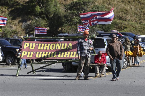 FILE - In this July 14, 2019, file photo, native Hawaiian activists gather at the base of Hawaii's Mauna Kea. Opponents of the Thirty Meter Telescope project on Hawaii island have left their camp because of concerns over the spread of the coronavirus. The Honolulu Star-Advertiser reports the move came after more than eight months of nonviolent protests at the base of the Mauna Kea Access Road. (AP Photo/Caleb Jones, File)