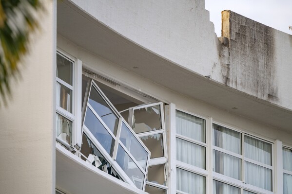 A broken window hands precariously at the Double Tree by Hilton Hotel in Cairns, Australia, after a helicopter crashed into its roof early Monday, Aug. 12, 2024. (Brian Cassey/AAP Image via AP)