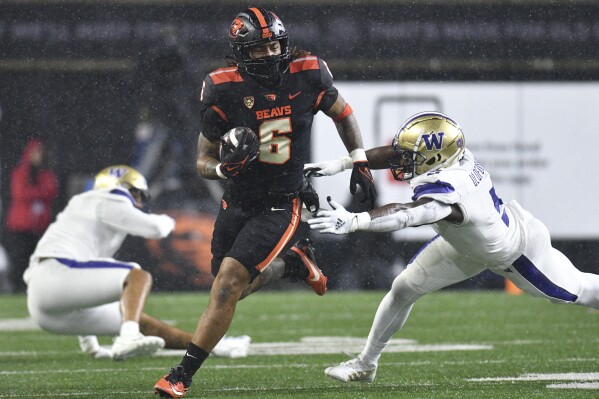 Oregon State running back Damien Martinez (6) is brought down by Washington linebacker Edefuan Ulofoshio (5) during the first half of an NCAA college football game Saturday, Nov. 18, 2023, in Corvallis, Ore. (AP Photo/Mark Ylen)