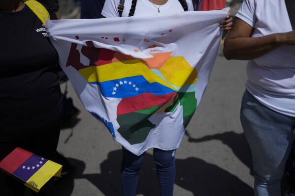 A woman holds a flag during a voting rehearsal for the upcoming December referendum for the territorial dispute between Guayana and Venezuela in Caracas, Venezuela, Sunday, Nov. 19, 2023. (AP Photo/Ariana Cubillos)