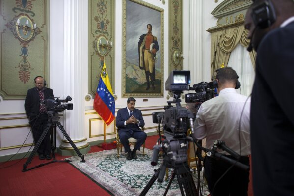 
              Venezuela's President Nicolas Maduro speaks during an interview with The Associated Press at Miraflores presidential palace, where a painting of independence hero Simon Bolivar hangs, in Caracas, Venezuela, Thursday, Feb. 14, 2019. Maduro is inviting a U.S. special envoy to come to Venezuela after revealing during the interview that his foreign minister recently held secret meetings with the U.S. official in New York. (AP Photo/Ariana Cubillos)
            