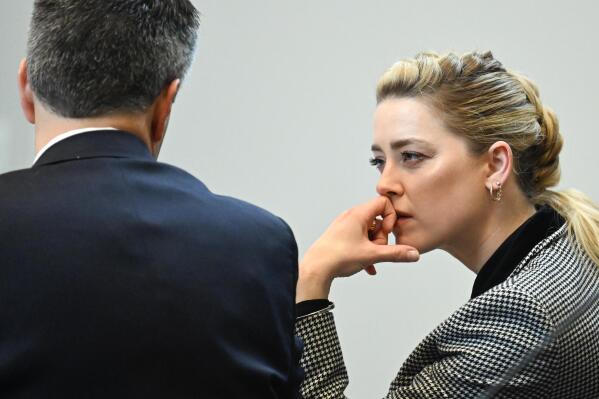 Actor Amber Heard speaks with a legal team member at the Fairfax County Circuit Courthouse in Fairfax, Va., Tuesday, May 24, 2022. Depp sued his ex-wife Amber Heard for libel in Fairfax County Circuit Court after she wrote an op-ed piece in The Washington Post in 2018 referring to herself as a "public figure representing domestic abuse." (Jim Watson/Pool photo via AP)