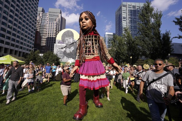 Little Amal, a 12-foot puppet of a 10-year-old Syrian refugee girl, is greeted by a crowd, Thursday, Sept. 7, 2023, in Boston. The puppet is scheduled to journey across the United States, with planned stops in over 35 towns and cities, between Sept. 7 and Nov. 5, 2023, in an effort to raise awareness about refugees and displaced people across the world. (AP Photo/Steven Senne)