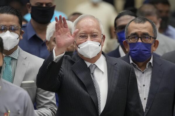 FILE - Former Malaysian Prime Minister Najib Razak, center, wearing a face mask, waves as he arrives at the Court of Appeal in Putrajaya, Malaysia, Tuesday, Aug. 23, 2022. Jailed Malaysian ex-Prime Minister Najib Razak returned to court Thursday for a second corruption trial over the pilfering of the 1MDB state fund, two days after he began a 12-year prison term for graft. (AP Photo/Vincent Thian, File)