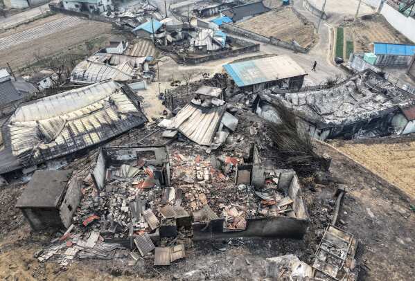 A person walks past houses destroyed by wildfires at a village in Yeongyang, South Korea, Wednesday, March 26, 2025. (Yun Kwan-shik/Yonhap via AP)