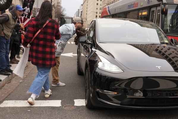 Demonstrators shout at a driver of a Tesla as they protest against the Trump administration near the White House Friday, March 14, 2025, in Washington. (AP Photo/Jacquelyn Martin)