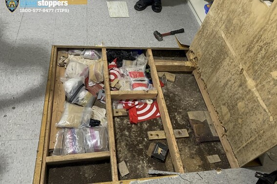 In this photo provided by the New York City Police Department, a trap door leans open over narcotics, including fentanyl, and drug paraphernalia stored in the floor of a day care center, Thursday, Sept. 21, 2023, in New York. Police say the owners of the New York City day care center where a toddler died and three others were sickened by opioid exposure the week before were hiding the bags of fentanyl concealed by plywood and tile flooring. (Courtesy NYPD via AP)