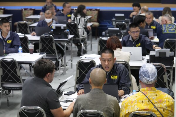 Foreigners, accused of operating a business without a permit, are summoned at Central Investigation Bureau in Bangkok, Thailand, Friday, May 31, 2024. Thai police have broken up a large network that illegally helped foreigners, mostly Russians, to stay in Thailand long-term through the use of company nominees or shell companies, officials said Friday. (AP Photo/Sakchai Lalit)