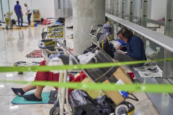 A person eats sitting on the floor of Terminal 4 at Adolfo Suarez-Madrid Barajas Airport in Madrid, Spain, Thursday, May 15, 2025. (AP Photo/Manu Fernandez)