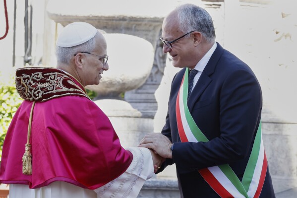Pope Leo XIV is greeted by Rome's Mayor Roberto Gualtieri at the foot of Capitoline Hill, in Rome, Sunday, May 25, 2025. (AP Photo/Riccardo De Luca)