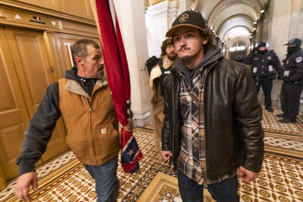 FILE - Insurrectionists loyal to President Donald Trump, including Kevin Seefried, left, walk on a hallway after a confrontation with Capitol Police officers outside the Senate Chamber inside the Capitol, Jan. 6, 2021 in Washington. A federal judge on Wednesday, June 15, 2022, convicted Kevin Seefried and his adult son Hunter Seefried of charges that they stormed the U.S. Capitol together to obstruct Congress from certifying President Joe Biden’s 2020 electoral victory. (AP Photo/Manuel Balce Ceneta, File)
