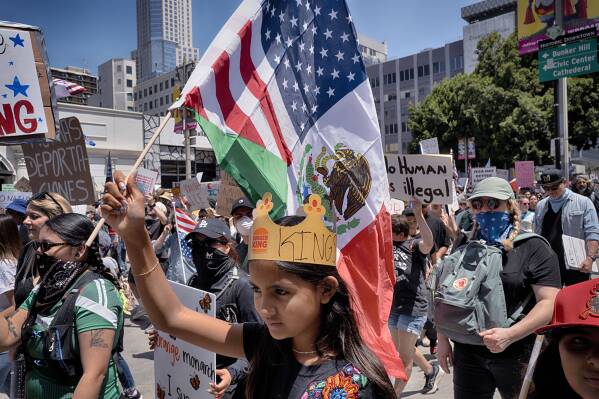 A young protester carries a combination Mexican and U.S. flag during a "No Kings" protest in downtown Los Angeles on Saturday, June 14, 2025. (AP Photo/Richard Vogel)