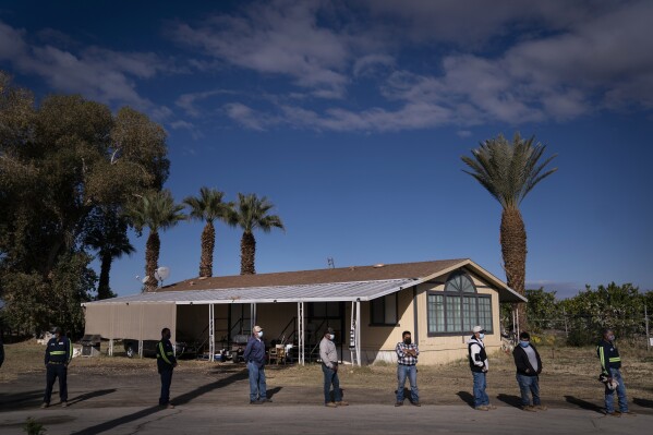 FILE - Farm workers wait in line at Tudor Ranch in Mecca, Calif., Jan. 21, 2021. Every year, heat kills more people than floods, hurricanes and tornadoes combined, and experts warn that extreme heat will become more intense, frequent and lethal with climate change. (AP Photo/Jae C. Hong, File)