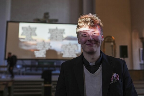 The Rev. Petja Kopperoinen poses for a photo, lit by the beams of a projector, during a rehearsal for an AI-created service at St. Paul's Lutheran church in Helsinki, Finland, Tuesday, March 4, 2025.