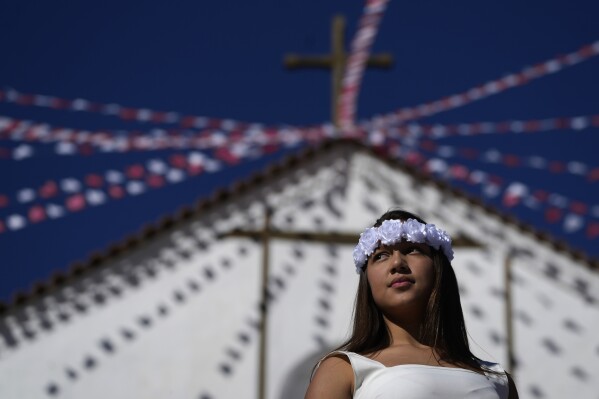 Una niña se encuentra frente a la iglesia de Nuestra Señora del Rosario durante las Cavalhadas, o Fiesta del Espíritu Santo, en Pirenópolis, estado de Goiás, Brasil, el domingo 8 de junio de 2025. (Foto AP/Eraldo Peres)