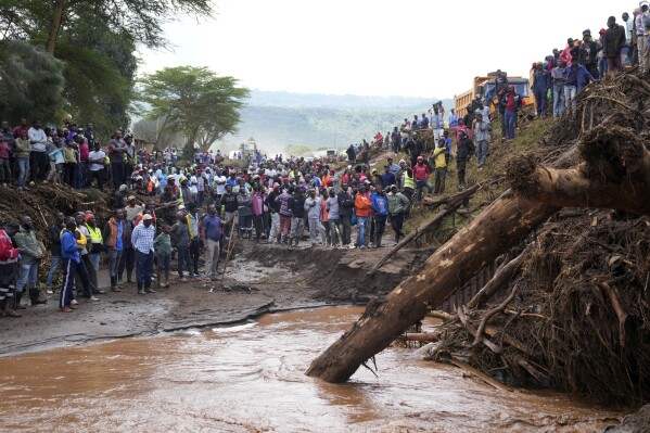 People gather on a bridge where a woman's body was retrieved, after floodwater washed away houses, in Kamuchiri Village Mai Mahiu, Nakuru County, Kenya, Tuesday, April 30, 2024. Kenya, along with other parts of East Africa, has been overwhelmed by flooding that killed 66 people on Monday alone and in recent days has blocked a national highway, swamped the main airport and swept a bus off a bridge. More than 150,000 people are displaced and living in dozens of camps. (AP Photo/Brian Inganga)