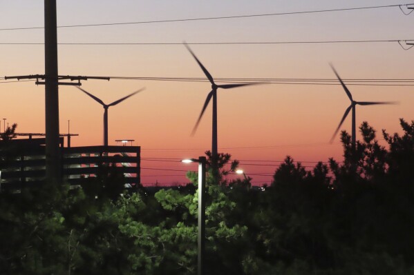 The sun sets behind spinning land-based wind turbines in Atlantic City, N.J. on Dec. 13, 2023. On Jan. 24, 2024, New Jersey utilities regulators approved two additional offshore wind farms, bringing the state's number to three. (AP Photo/Wayne Parry)