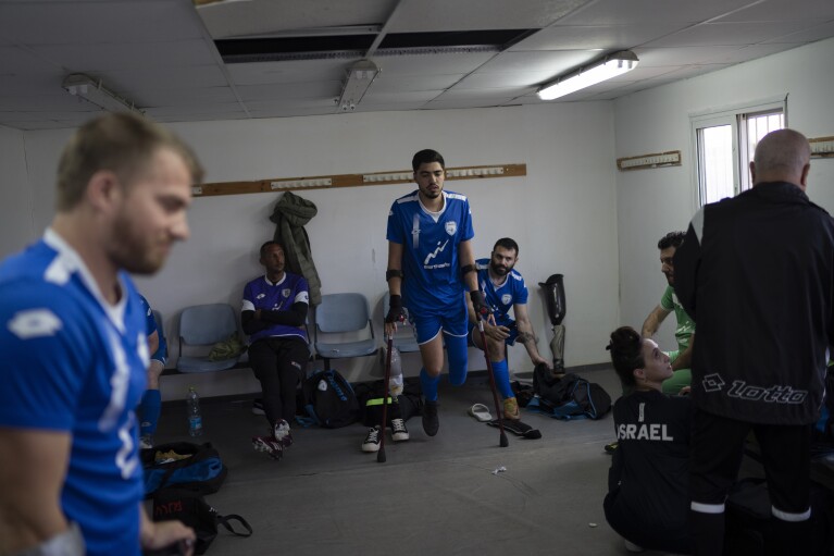 The soccer player of Israel Amputee Football Team, Omer Glikstal, center, gets ready for a practice session in Ramat Gan, Thursday, April 11, 2024. The team practices two evenings a week at the stadium in the Tel Aviv suburb of Ramat Gan, first with warm-ups and drills, then practice games - each man undeterred by the absence of an arm or a leg from an accident, a war injury or a birth defect. (AP Photo/Leo Correa)