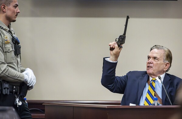 Santa Fe County Deputy Levi Abeyta, left, watches as expert witness for the defense Frank Koucky III demonstrates how to uncock a gun like the one used on the set of the movie 
