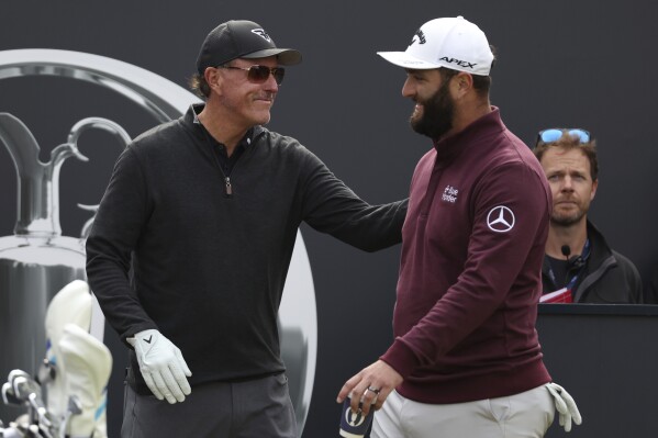 FILE - Spain's Jon Rahm, right greets United States' Phil Mickelson on the 1st tee during a practice round for the British Open Golf Championships at the Royal Liverpool Golf Club in Hoylake, England, Wednesday, July 19, 2023. The Open starts Thursday, July 20. Rahm has been saying that he plays golf for history and for legacy, not for money. And now he's playing for the Saudi-funded LIV Golf League in a shocking departure from the PGA Tour. (AP Photo/Peter Morrison, File)