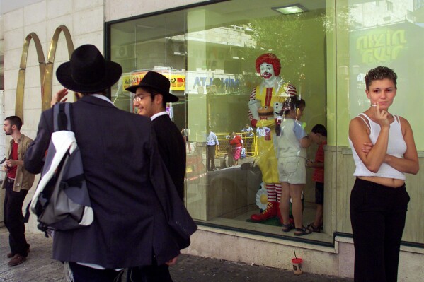 FILE - Residents of Jerusalem mingle inside and outside of the city's downtown McDonald's fast food restaurant Friday Aug. 16, 2002. McDonald’s is buying its restaurants in Israel from a longtime franchisee, hoping to reset sales that have slumped due to boycotts in the region. (AP Photo/David Guttenfelder, File)